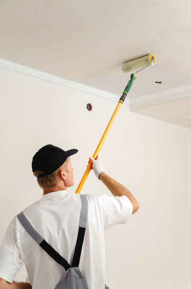 A contractor painting the ceiling using a roller.
