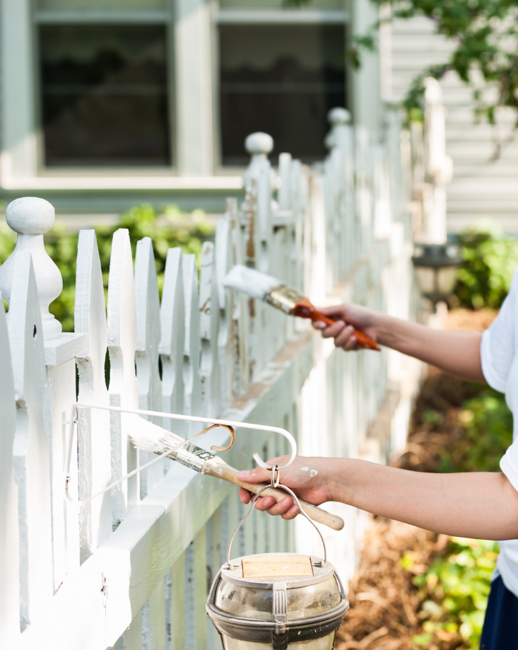 Painting a white picket fence.
