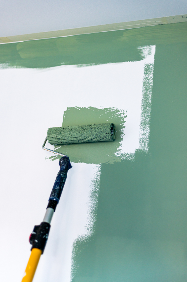 Painting the wall with green paint using a roller.