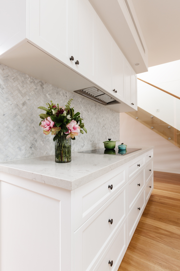White kitchen cabinet details with a flower vase on the countertop.