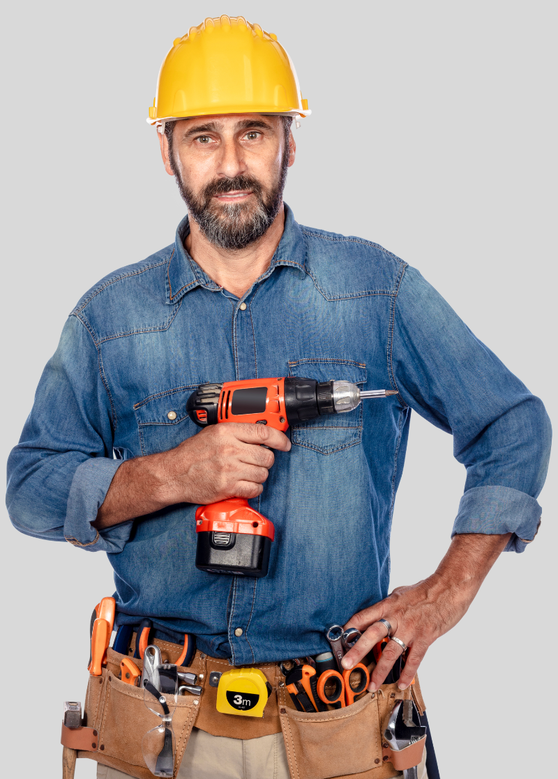Un homme portant un casque de sécurité tient une perceuse.