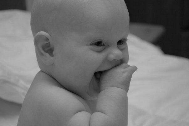 A montessori infant is sitting on a bed.