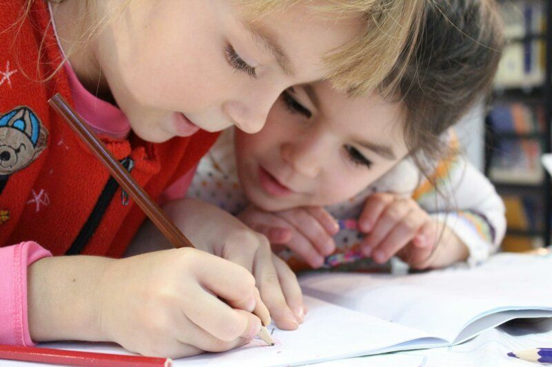 Two young montessori childrens are working together.