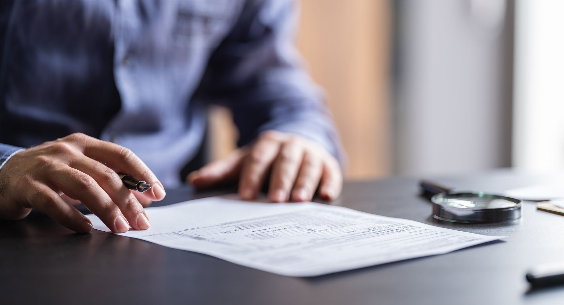 A man is sitting at a desk writing on a piece of paper.