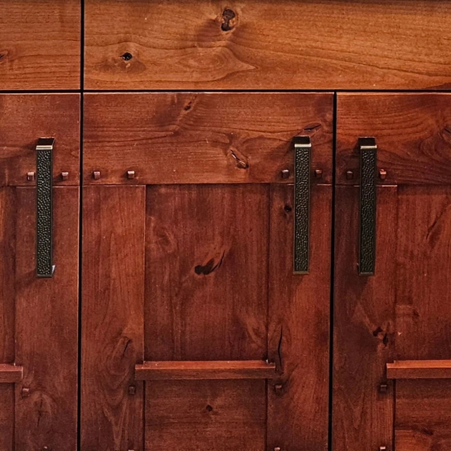 A close up of a wooden cabinet with black handles