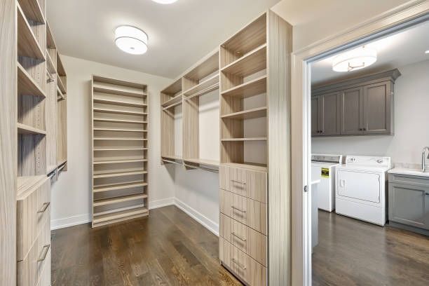 A walk in closet with lots of shelves and drawers next to a laundry room.