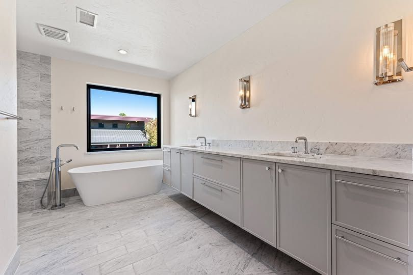 A bathroom with a tub , sink , and window.