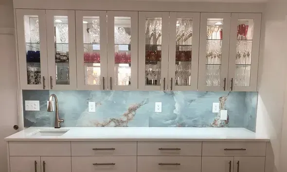 A kitchen with white cabinets , a sink , and a glass display case.