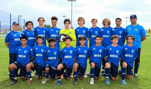 A soccer team is posing for a picture on a field.