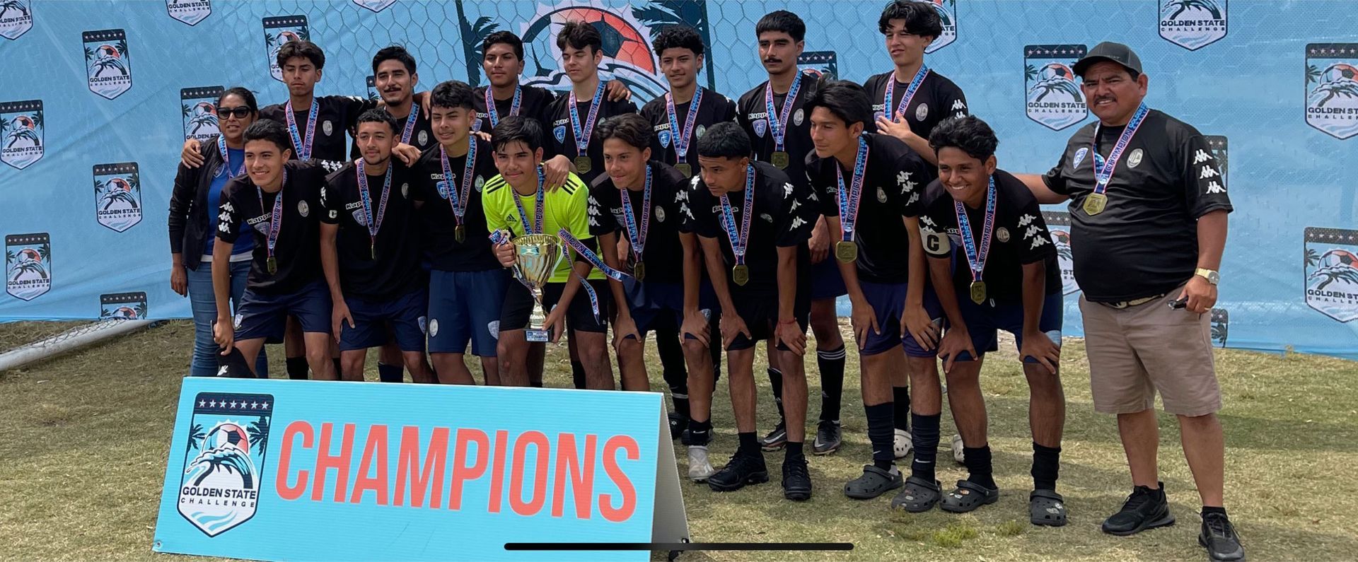 A soccer team is posing for a picture in front of a banner that says champions.
