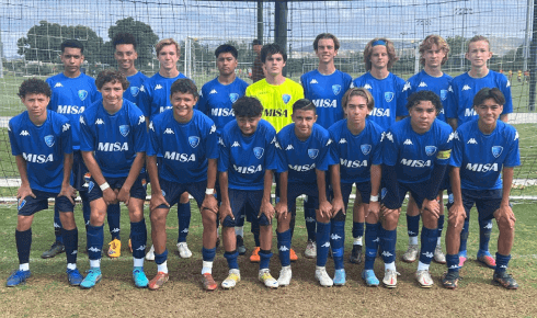 A soccer team is posing for a team photo on a field.