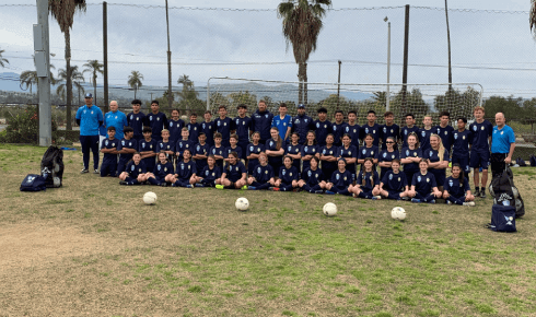 A group of soccer players are posing for a picture on a field.