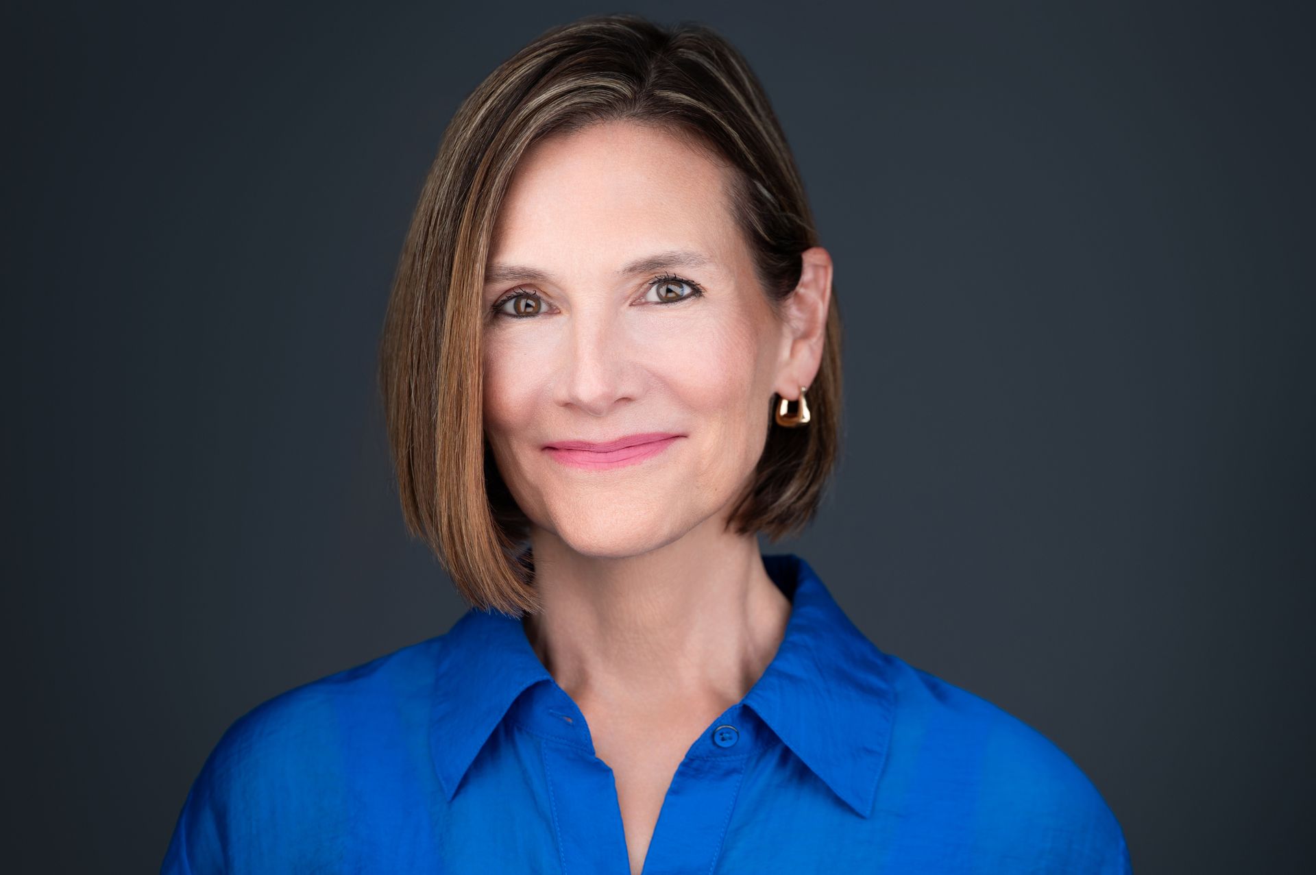Woman with shoulder-length brown hair smiles at the camera. 