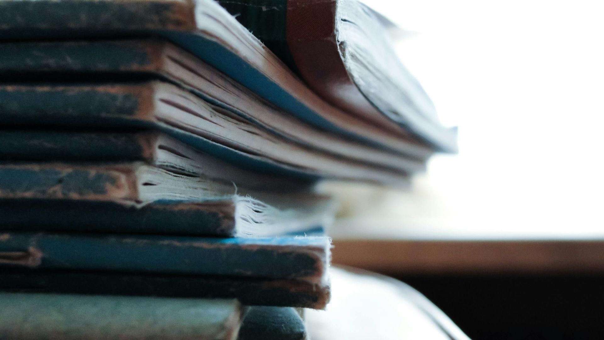 Stack of blue-covered books with worn edges, in a room with bright light.