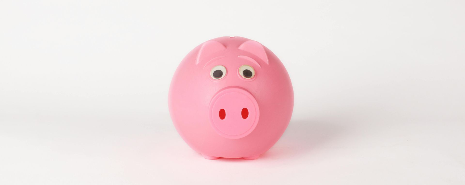 A pink, spherical piggy bank with simple eyes and a snout centered on a plain white background.