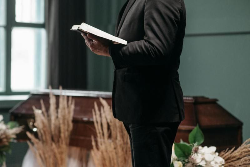 A man is standing in front of an open bible in a church.