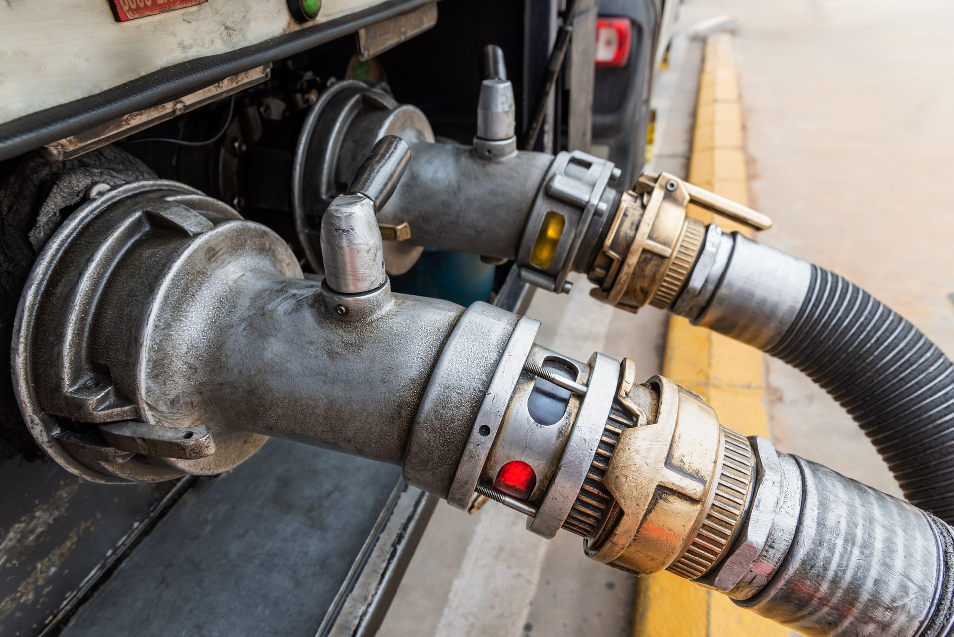 A close up of a hose attached to a truck at a gas station.