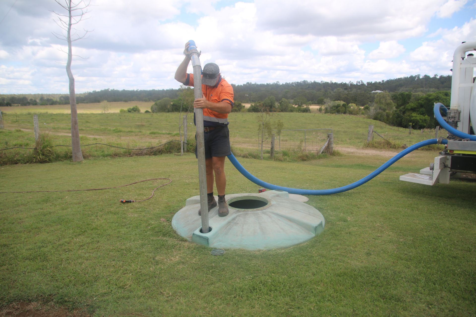 A man is pumping a hose into a septic tank.