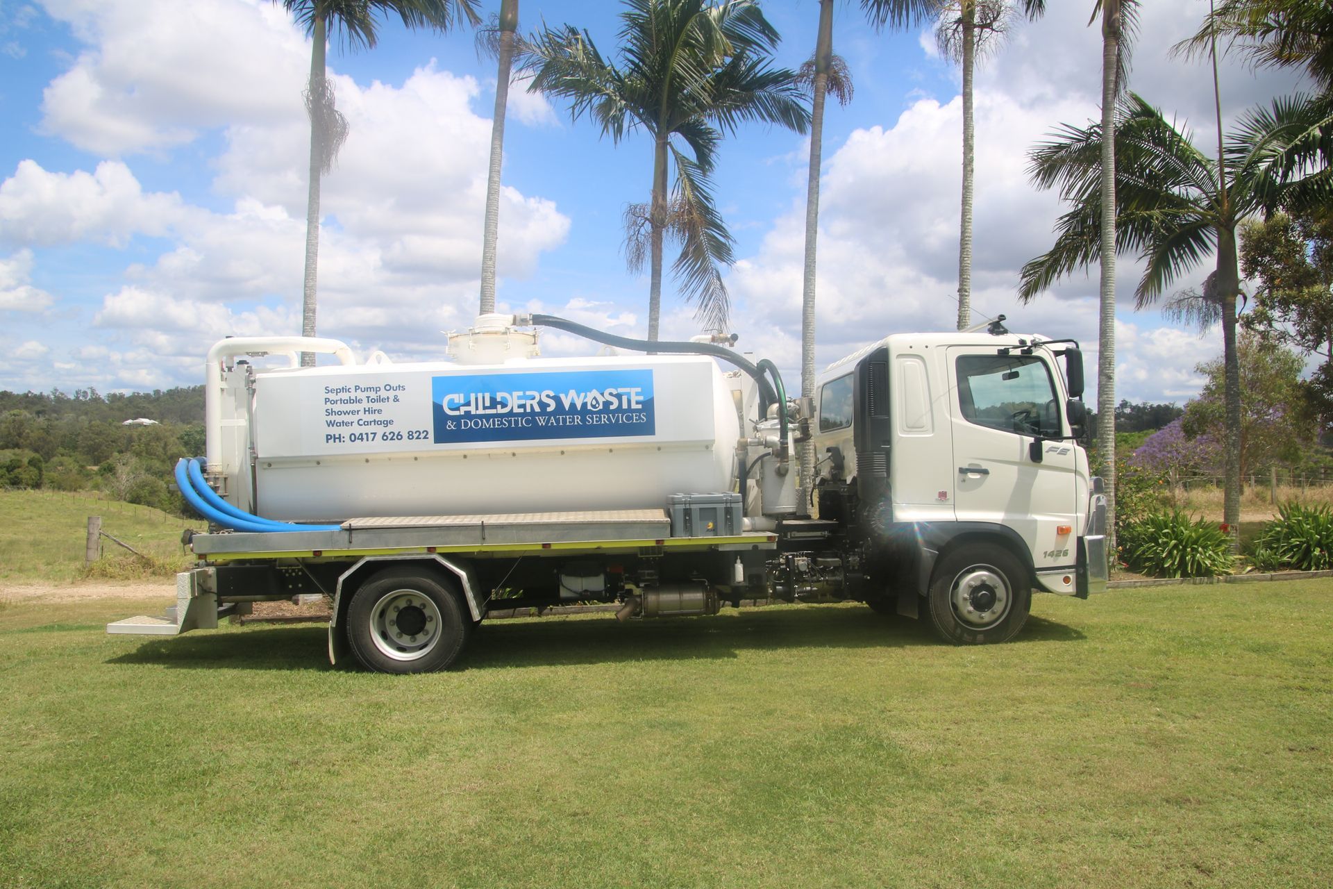 A man wearing red rubber gloves is opening a manhole cover.