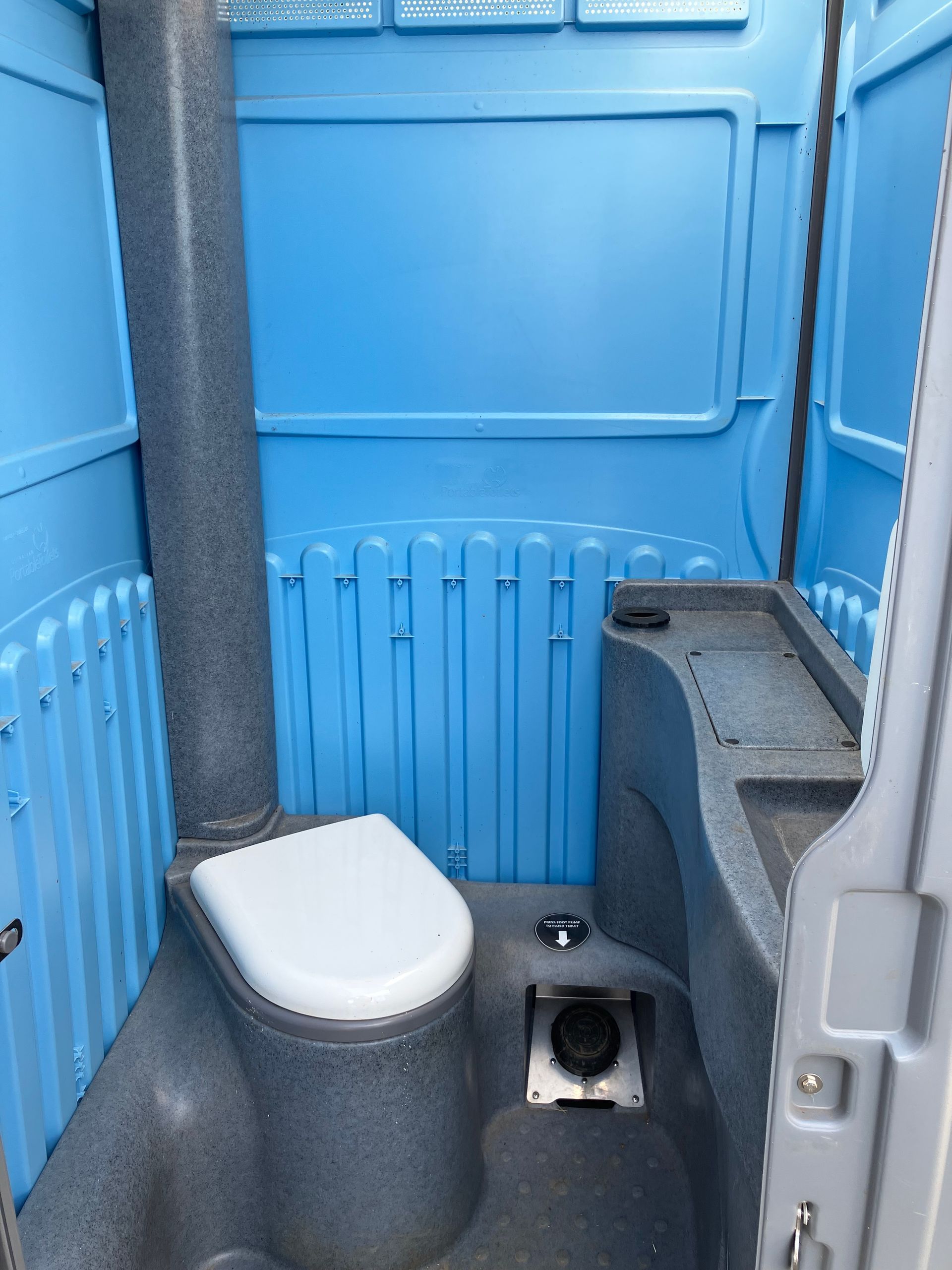 A row of blue portable toilets are lined up on a sidewalk.