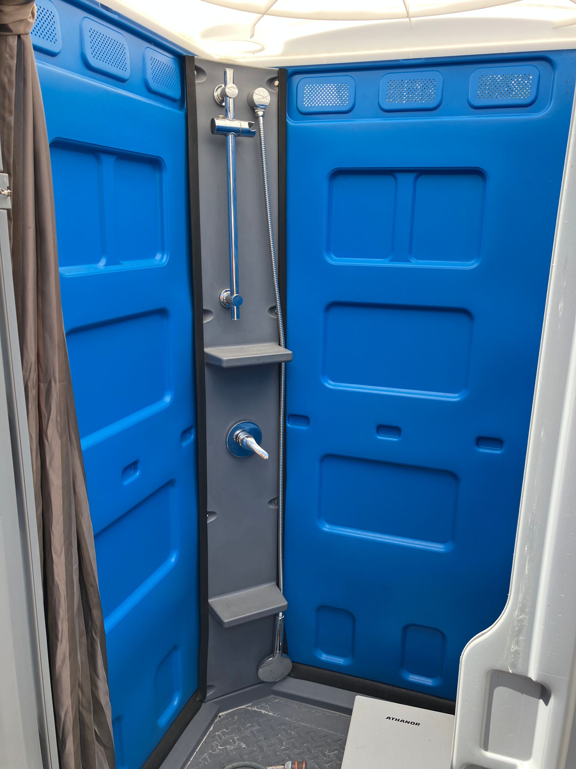 A green truck is carrying a trailer full of portable toilets