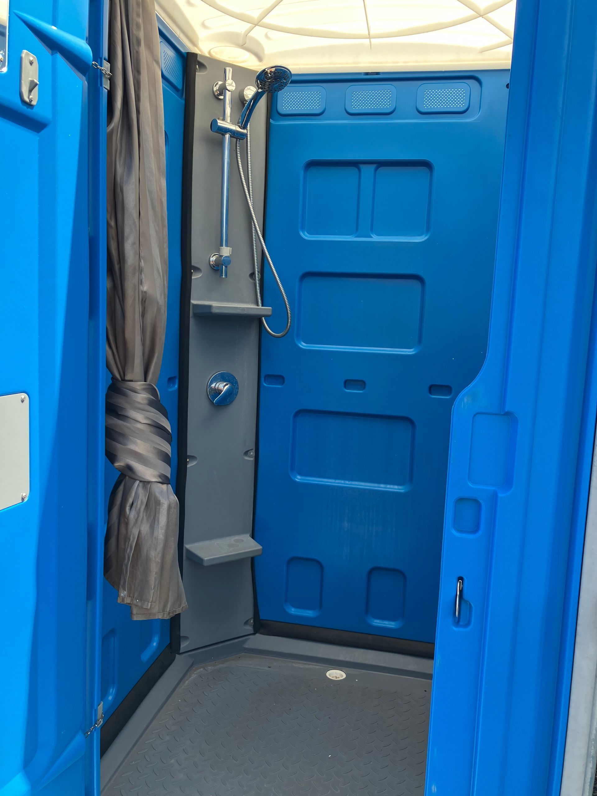 Two blue portable toilets are sitting next to each other in a park.