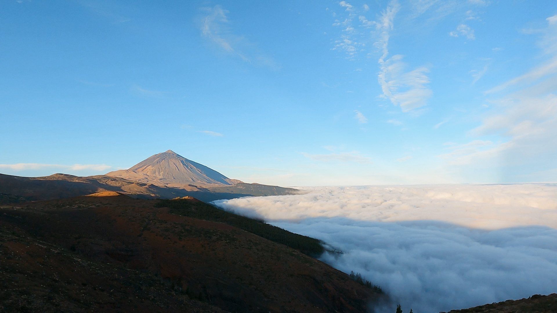 Ein wolkenverhangener Berg mit blauem Himmel im Hintergrund.
