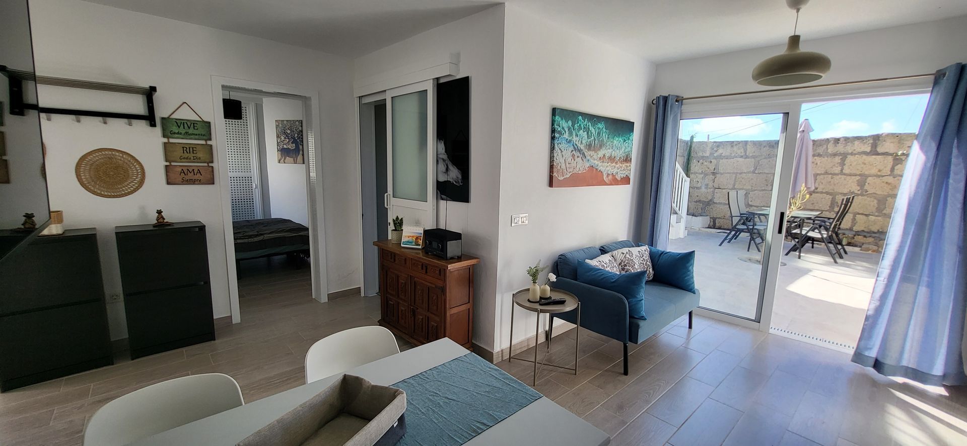 Das Wohnzimmer mit Tisch und Stühlen und einer Glasschiebetür, die auf die Terrasse führt.