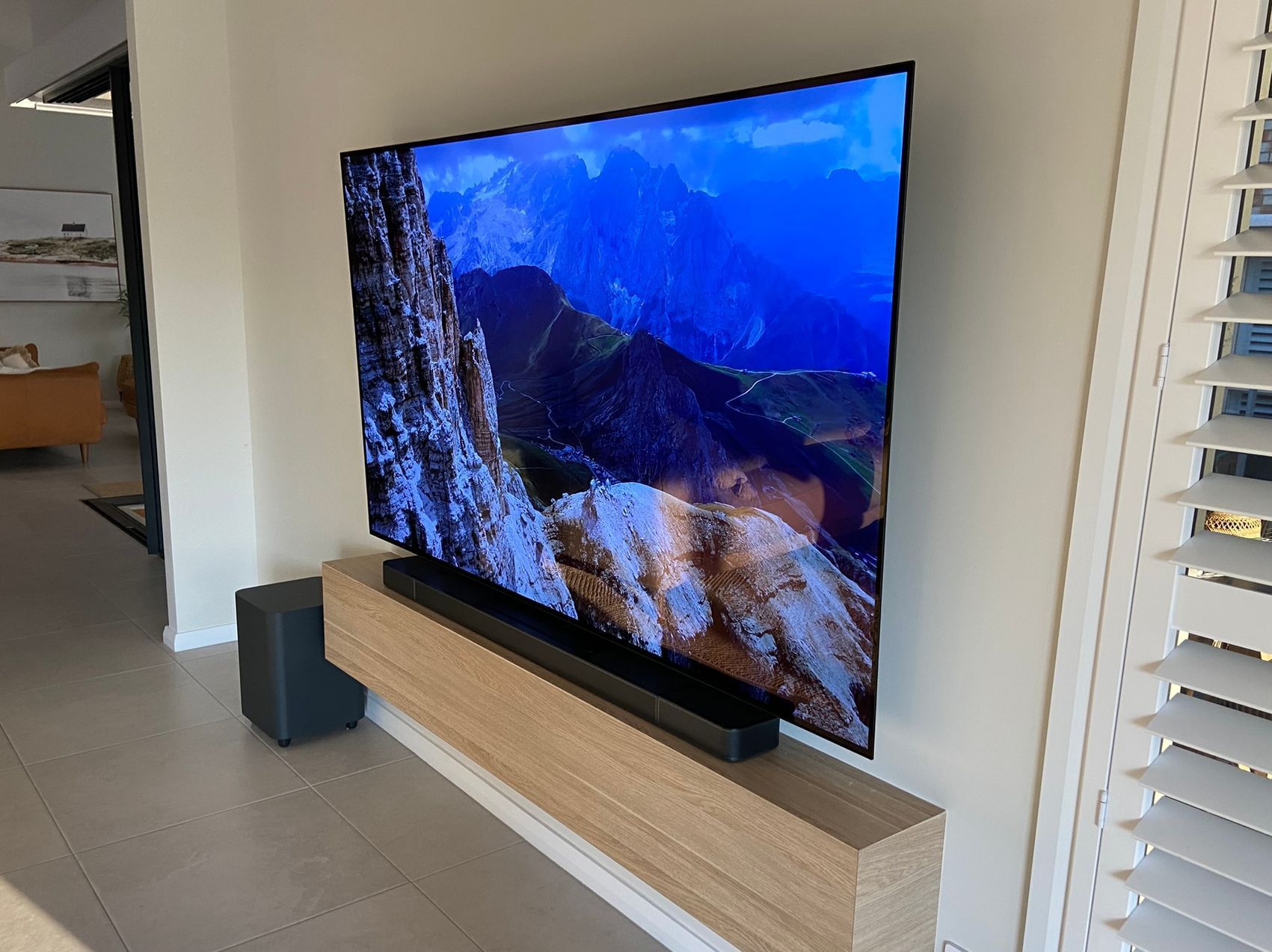 A large flat screen tv is mounted on a wall in a living room.