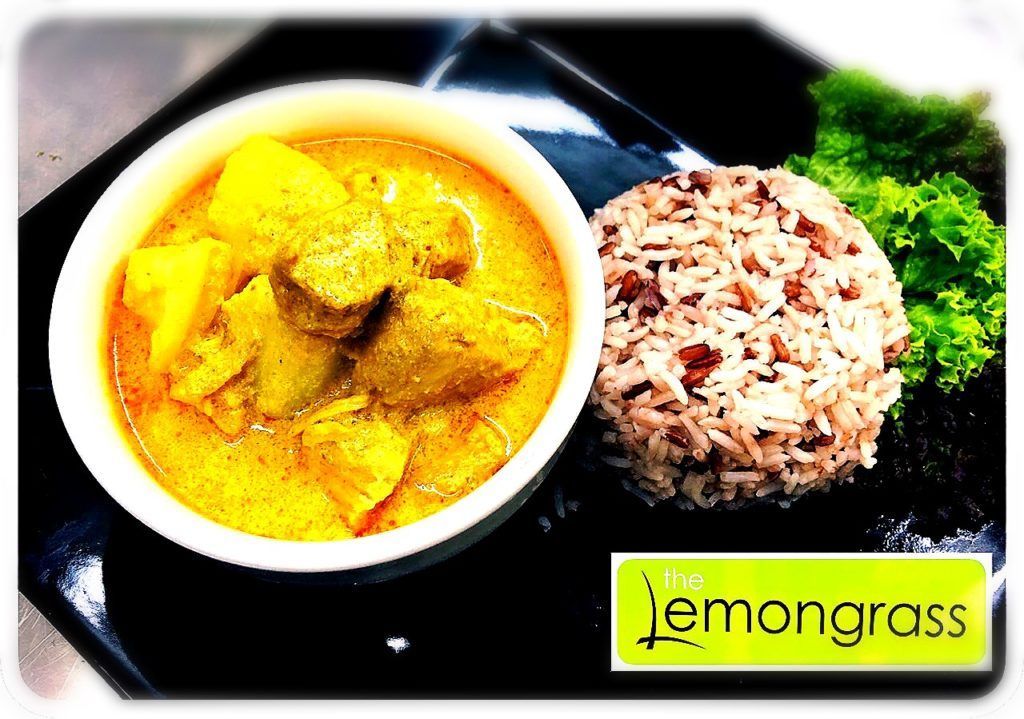 A bowl of yellow curry next to a plate of brown rice.