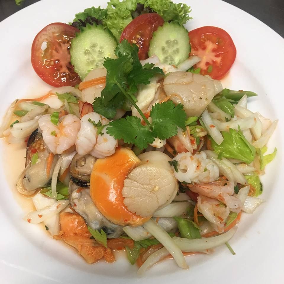 A white plate topped with shrimp scallops tomatoes and cucumbers