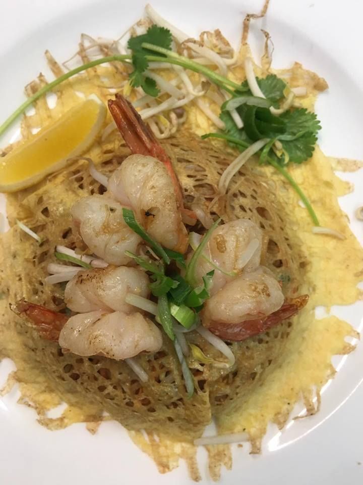A close up of a plate of food with shrimp and vegetables on a table.