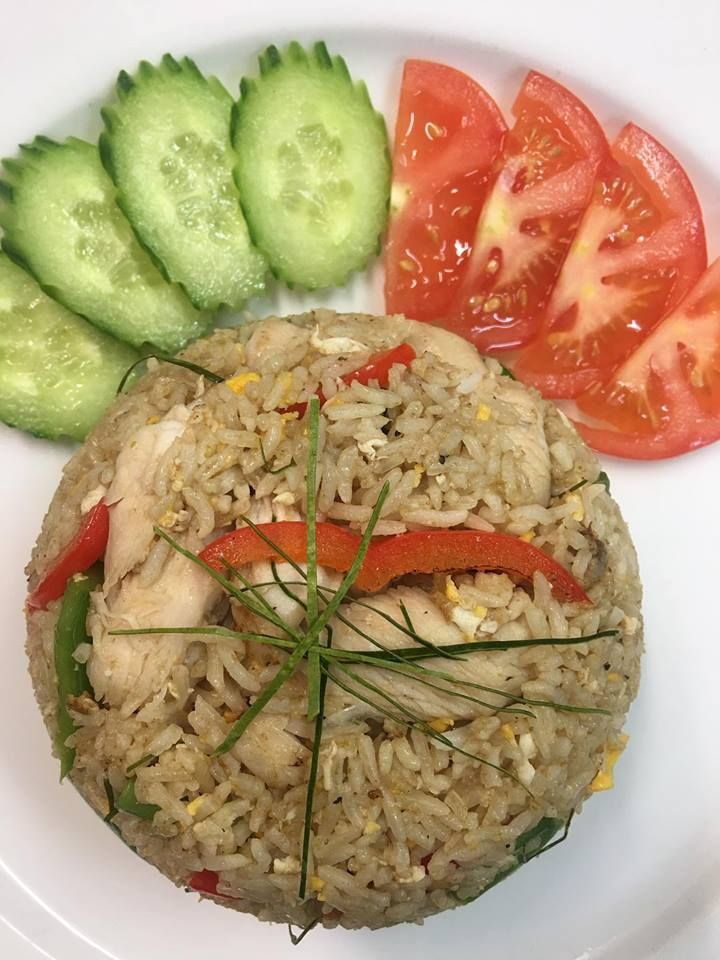 A white plate topped with rice , tomatoes and cucumbers.