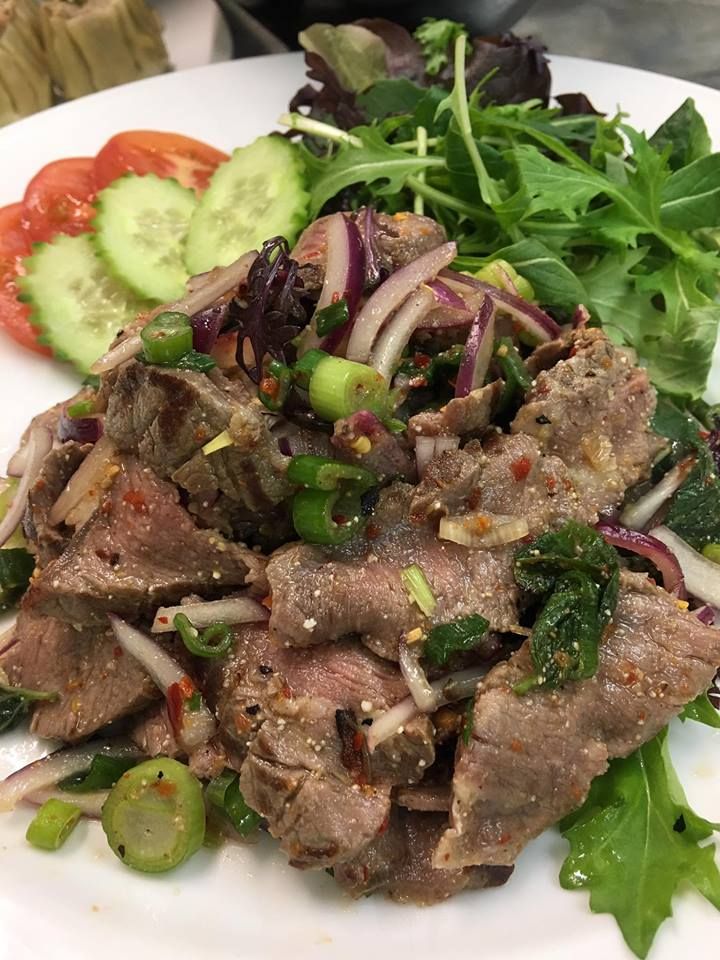 A close up of a plate of food with meat and vegetables on a table.