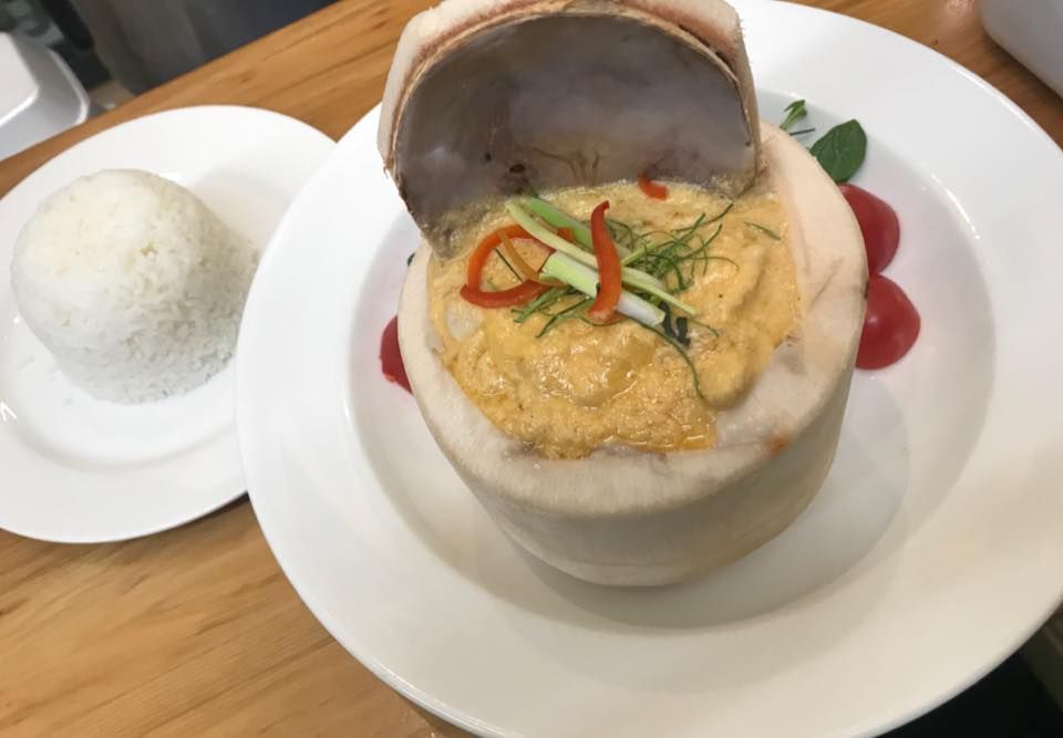 A white plate topped with a bowl of food next to a bowl of rice.