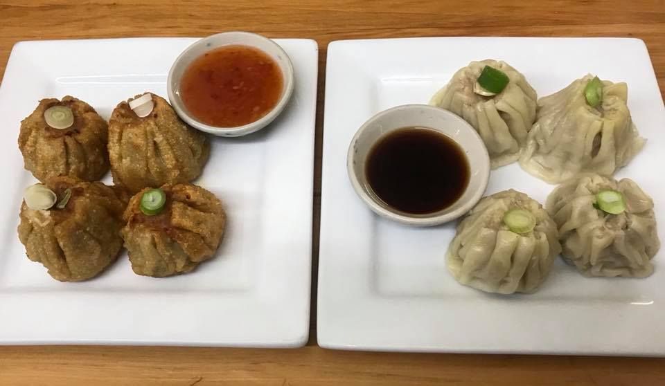 Two plates of food with dipping sauce on a wooden table.