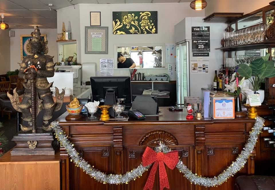 The front desk of a restaurant decorated for christmas with a red bow.