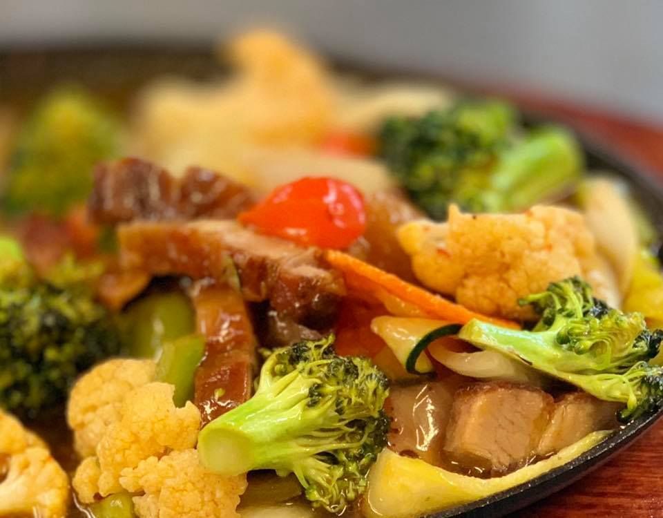 A close up of a plate of food with broccoli and cauliflower on a wooden table.
