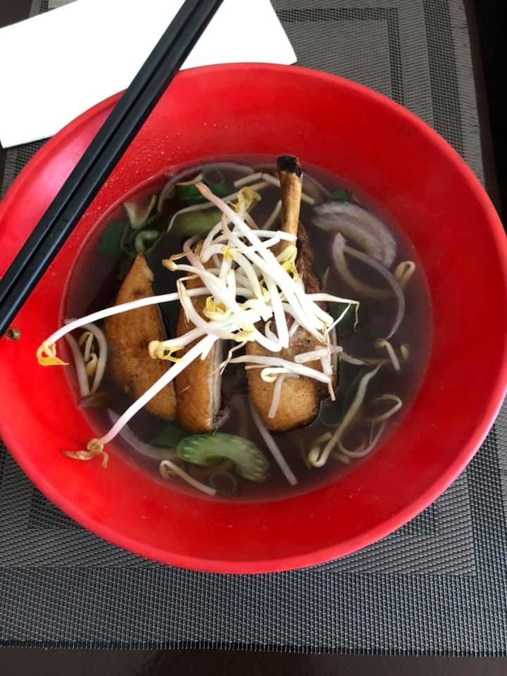 A bowl of soup with chopsticks on a table