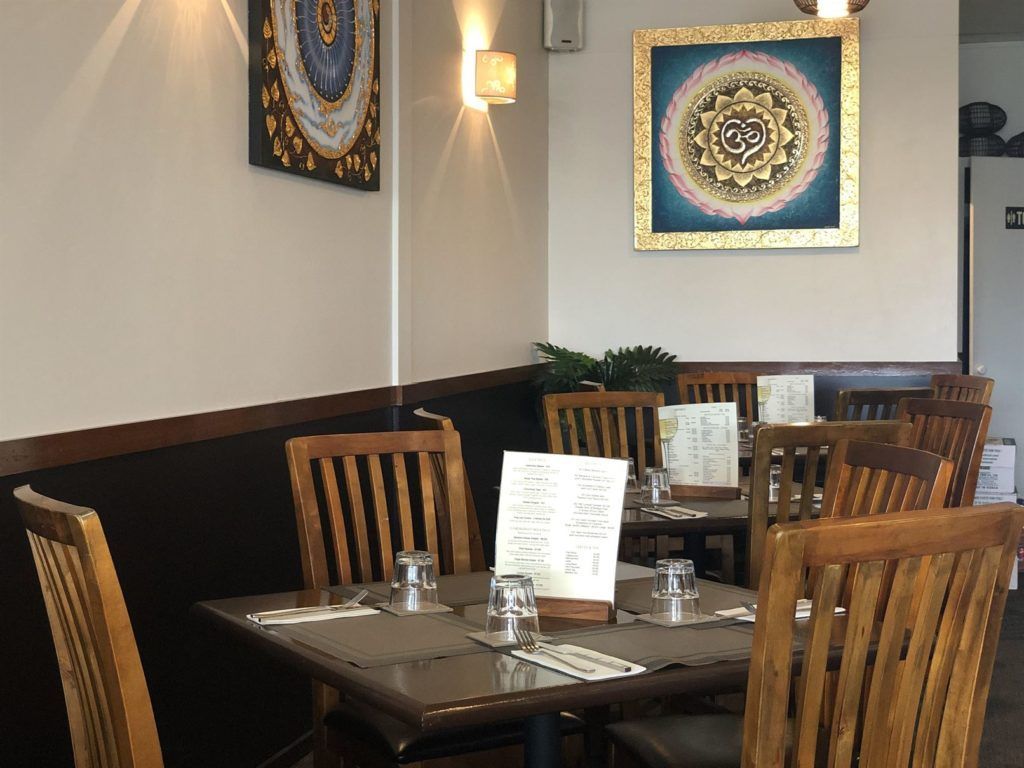 A restaurant with tables and chairs and a painting on the wall.