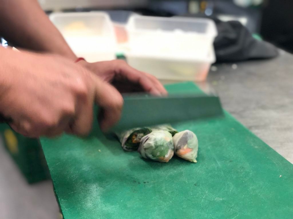 A person is cutting vegetables on a green cutting board.