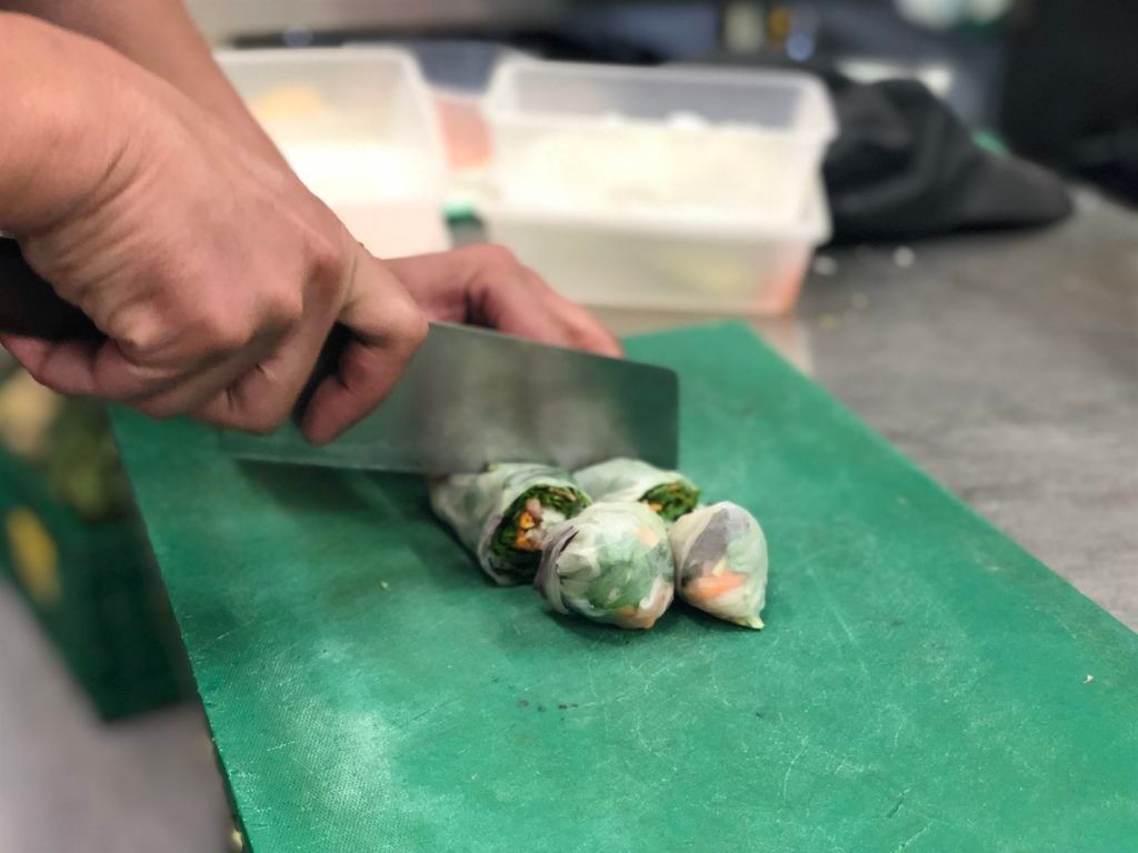 A person is cutting food on a green cutting board.
