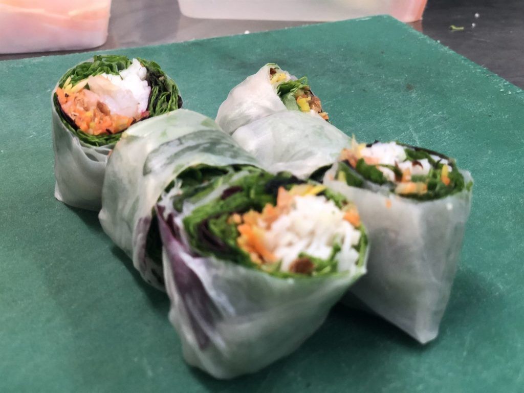 A bunch of vegetable rolls are sitting on a green cutting board.