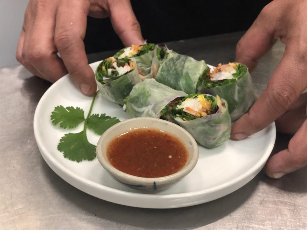A person is holding a plate of food with a dipping sauce on it.