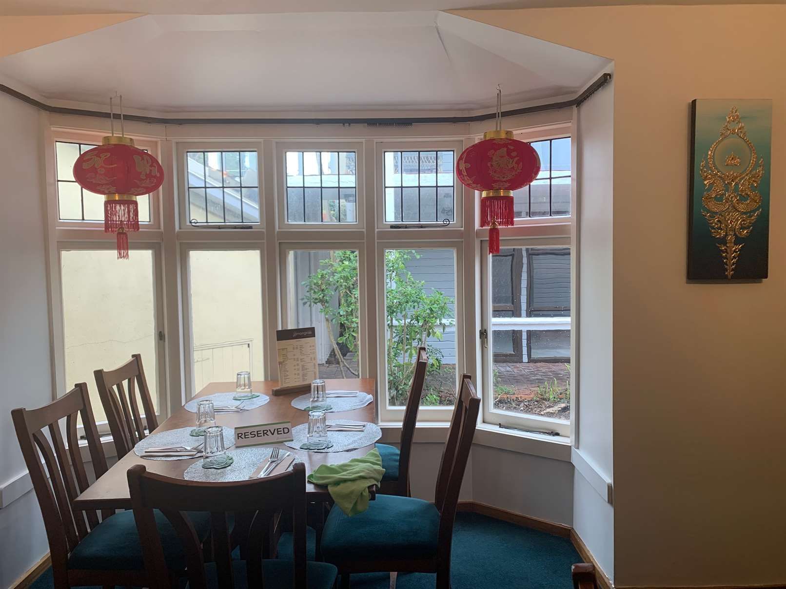 A dining room with a table and chairs and lanterns hanging from the ceiling.