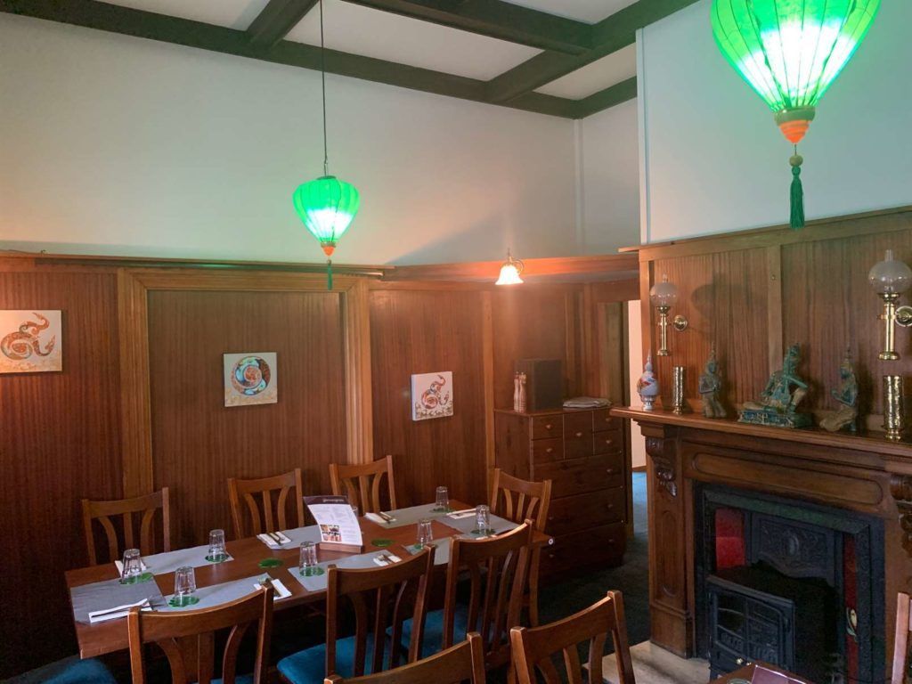 A dining room with a long table and chairs and a fireplace.