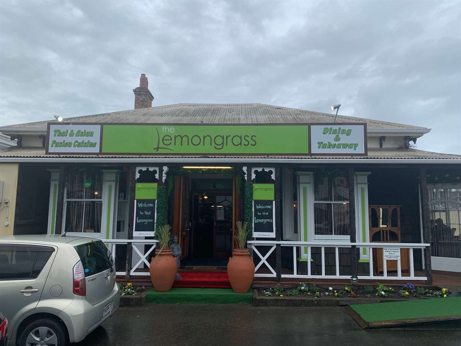 A car is parked in front of a restaurant called lemongrass.