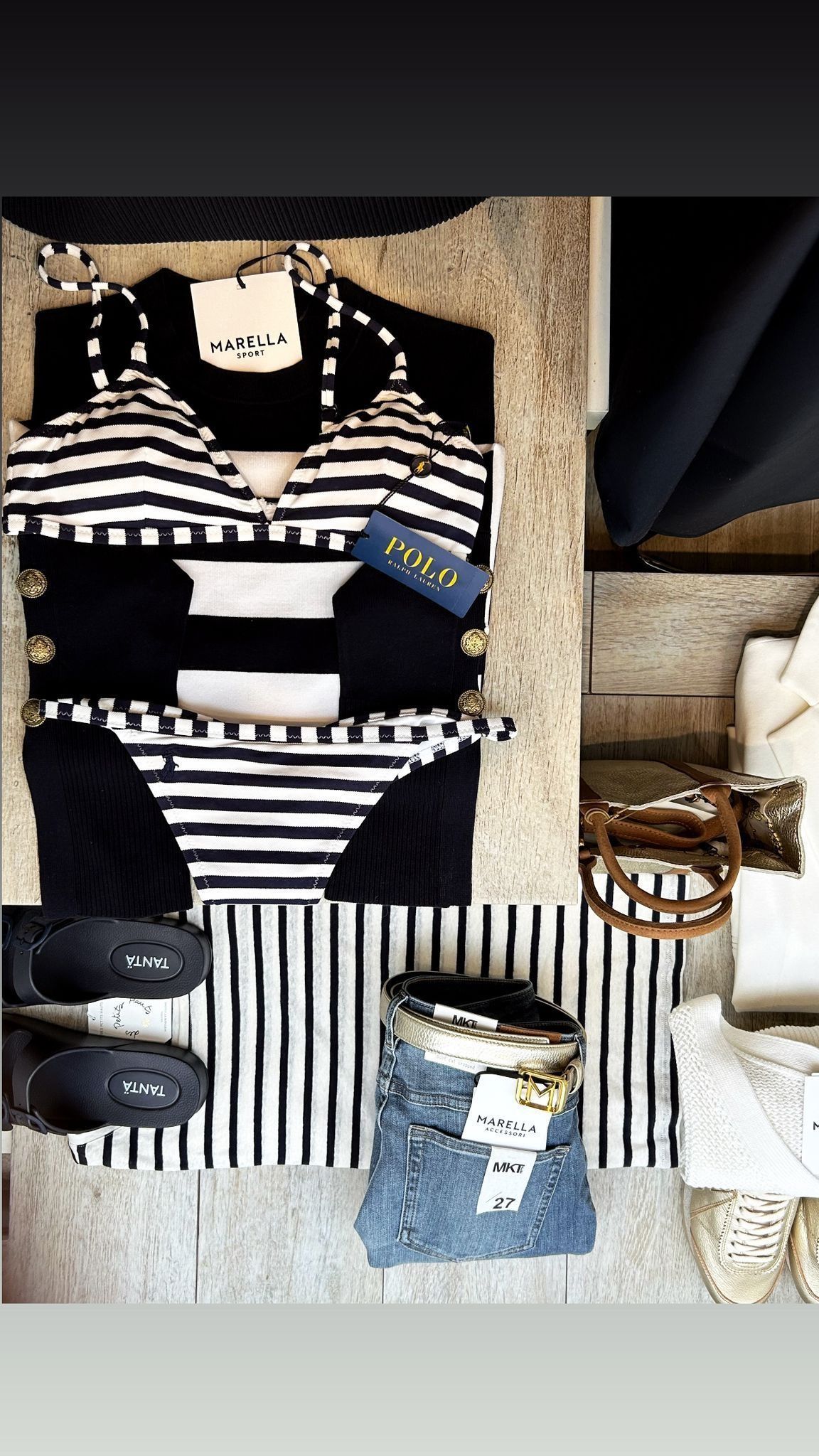 Bikini a righe bianche e nere con accessori, disposti su una superficie testurizzata.