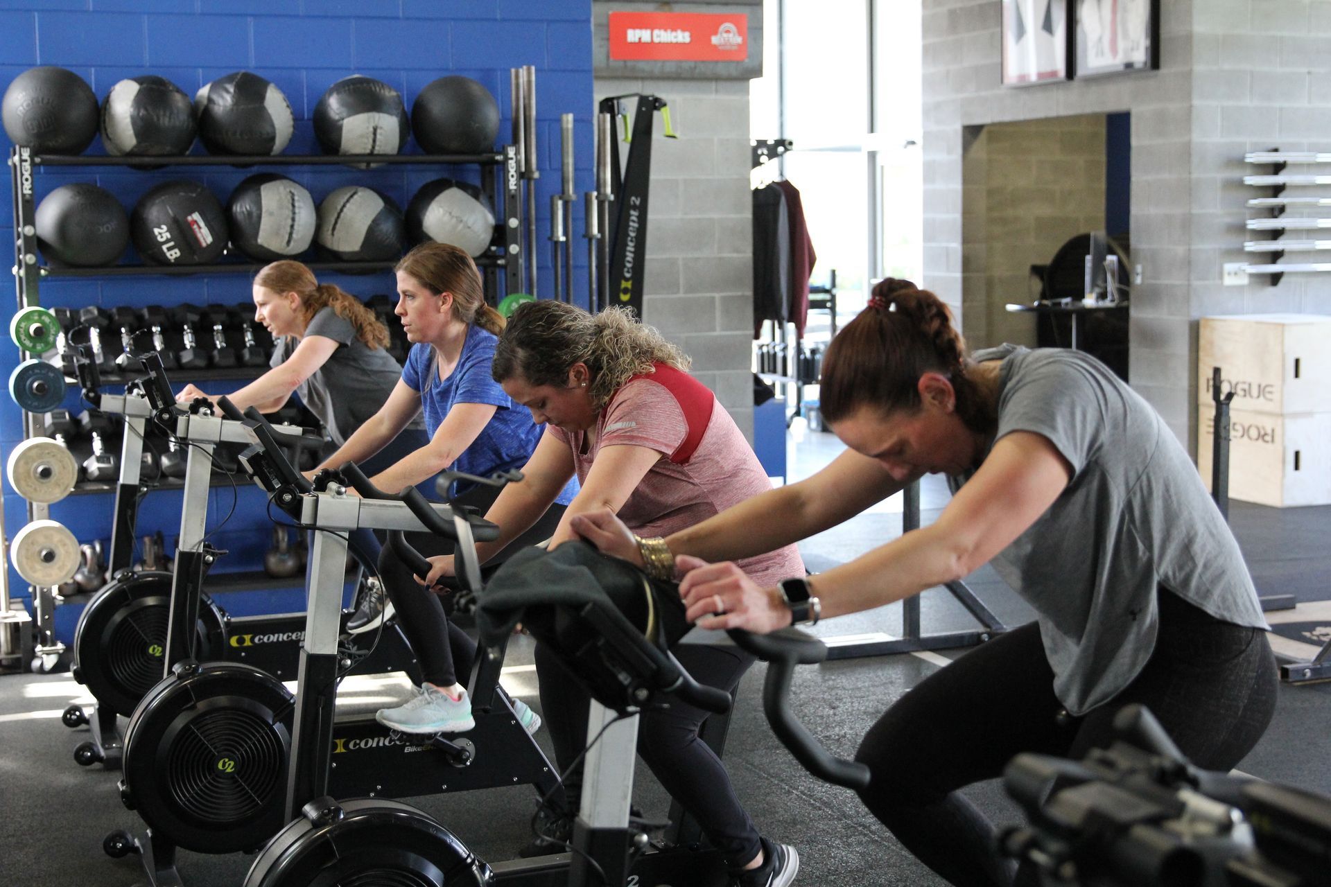 A group of women are riding exercise bikes in a gym.