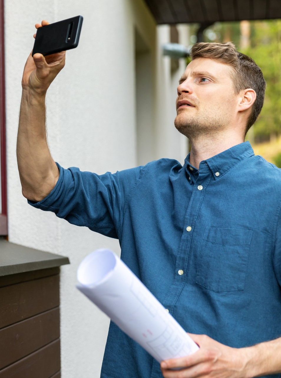 Une personne en chemise à carreaux écrit sur un bloc-notes, debout près d'une fenêtre.